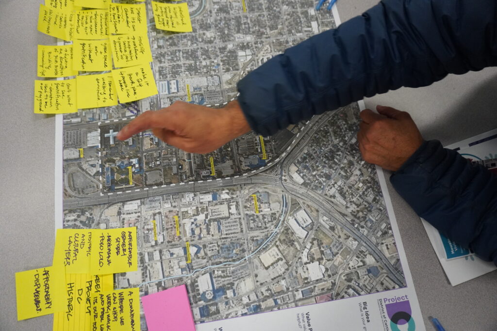 Residents pointing to sites on a Cattleman Square aerial map covered in sticky-note ideas – Project DC urban planning workshop by Urban Alchemy Collective